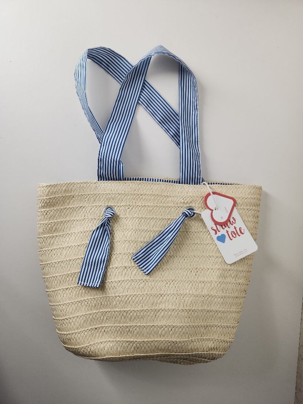 Woven straw tote bag with blue-and-white striped fabric handles